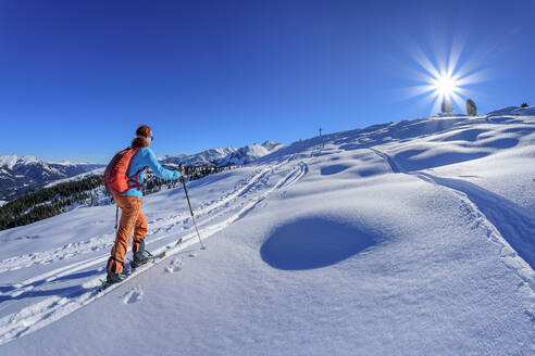 Austria, Tyrol, Female skier ascending snowcapped slope of Schonbichl - ANSF00226