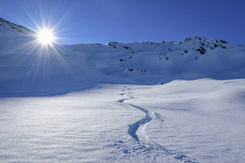 Österreich, Tirol, Sonnenschein über kurvenreicher Strecke im Schnee - ANSF00248