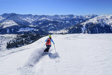 Österreich, Tirol, Skifahrerin rutscht schneebedeckten Hang in den Kitzbüheler Alpen hinunter - ANSF00259