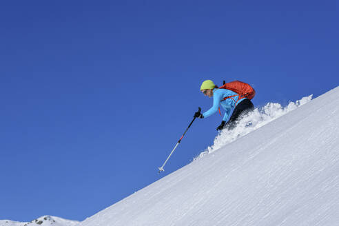 Österreich, Tirol, Skifahrerin rutscht schneebedeckten Hang in den Kitzbüheler Alpen hinunter - ANSF00260