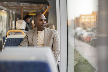 Thoughtful businessman looking through window in tram - JCCMF09269