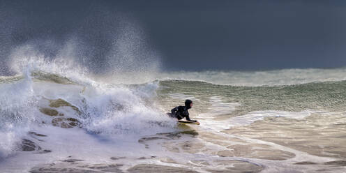 Mann schwimmt mit Surfbrett in welligem Meer im Urlaub - ALRF01977