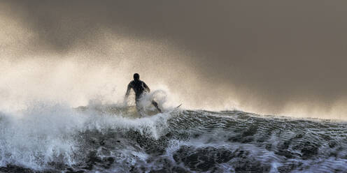 Unbekümmerter Surfer beim Surfen auf welligem Meer bei Sonnenuntergang - ALRF01981