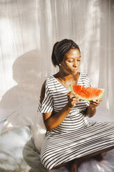 Schwangere Frau isst Wassermelone im Garten - PCLF00224