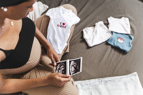 Schwangere Frau hält Ultraschalluntersuchung auf dem Bett zu Hause - PCLF00233