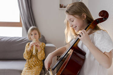 Glückliche Mädchen spielen zu Hause Musikinstrumente - VIVF00358