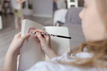 Mädchen zeichnet in Buch zu Hause - VIVF00388