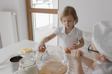 Children breaking eggs in mixing bowl - VIVF00389