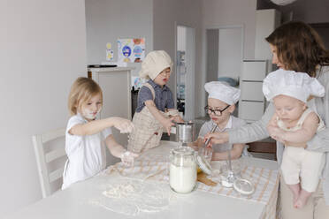 Mother with children having fun preparing dough in kitchen - VIVF00397