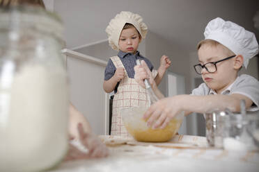 Boy mixing batter with wire whisk in kitchen - VIVF00404