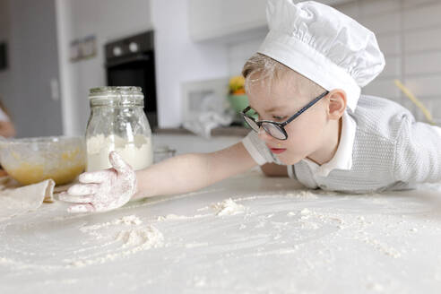 Junge spielt mit Mehl am Tisch in der Küche - VIVF00408
