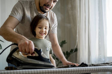 Father and son ironing clothes at home - ANAF00963