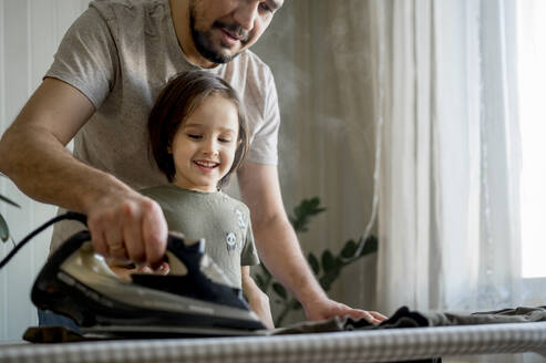Vater und Sohn beim Bügeln von Wäsche zu Hause - ANAF00963