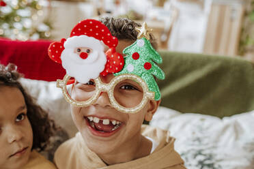 Glücklicher Junge mit Weihnachtsbrille und Schwester zu Hause - MDOF00571