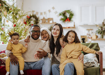 Glückliche Familie, die zu Weihnachten zusammen auf dem Sofa sitzt - MDOF00579