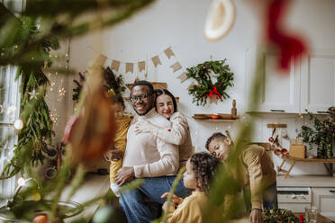 Glückliche Familie, die sich umarmt und sich in der Küche an Weihnachten vergnügt - MDOF00584