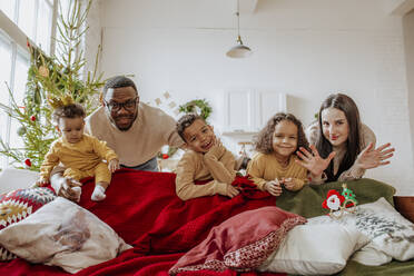 Glückliche Familie, die zu Weihnachten gemeinsam hinter dem Sofa steht - MDOF00591