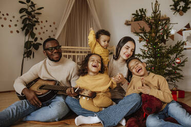 Cheerful family spending time together at Christmas playing the guitar - MDOF00601