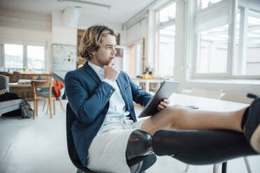 Thoughtful businessman with hand on chin sitting in office - JOSEF16519