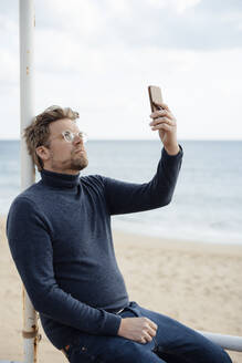 Mann benutzt Mobiltelefon am Strand - JOSEF16552