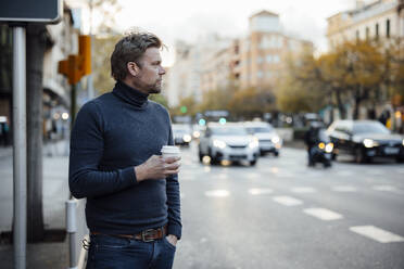 Nachdenklicher Mann mit Einweg-Kaffeebecher auf einer Straße in der Stadt - JOSEF16567