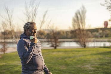 Älterer Mann, der eine Hantel hält und im Park bei Sonnenuntergang trainiert - JCCMF09300