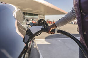 Hands of woman inserting plug into electric car - JCCMF09307