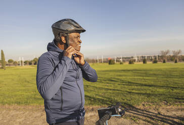 Nachdenklicher älterer Mann mit Helm an einem sonnigen Tag - JCCMF09312