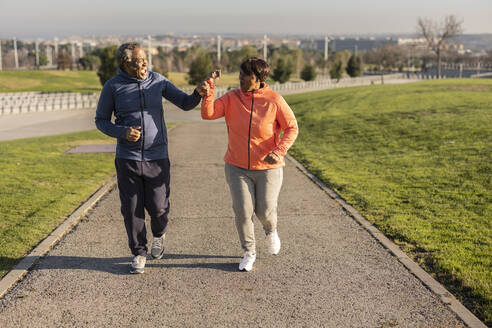 Glückliches Seniorenpaar beim Joggen auf dem Fußweg im Park - JCCMF09313