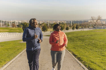 Happy senior couple running together on sunny day - JCCMF09314