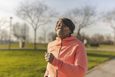 Ältere Frau joggt im Park an einem sonnigen Tag - JCCMF09317