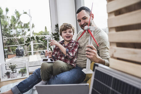 Vater und Sohn spielen zu Hause mit Windradmodellen - UUF28079