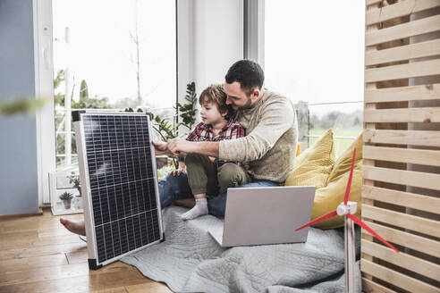 Vater und Sohn betrachten ein Solarpanel - UUF28083