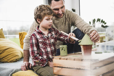 Father helping son painting model house at home - UUF28096