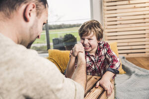 Father and son doing arm wrestling at home - UUF28115