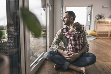 Nachdenklicher Vater sitzt mit seinem Sohn zu Hause auf dem Boden - UUF28135