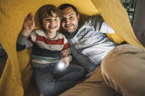 Glücklicher Vater und Sohn mit Fackel unter gelber Decke - UUF28151