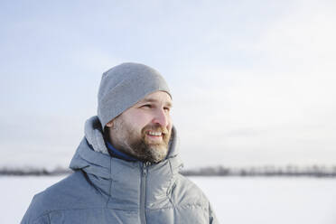 Glücklicher Mann mit Strickmütze im Winter unter freiem Himmel - EYAF02555