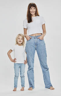 Lächelnde Mutter und Tochter mit Hand auf der Hüfte vor weißem Hintergrund - DHEF00676
