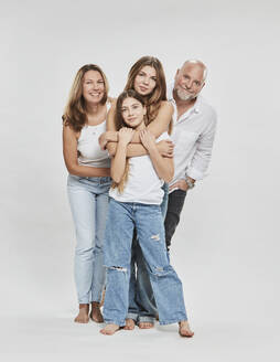 Glückliche Eltern mit Tochter stehen zusammen vor weißem Hintergrund - DHEF00695