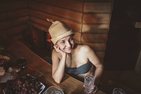 Lächelnde Frau mit Hut träumt in der Sauna - MDOF00603