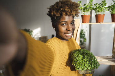 Smiling woman taking selfie with small vegetables at home - ALKF00081