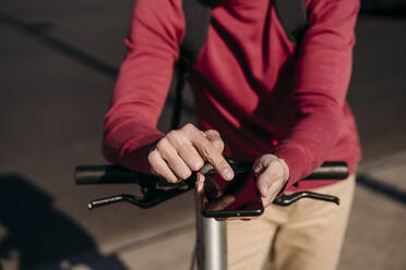 Junger Mann mit Elektro-Scooter und Smartphone - EBBF07835