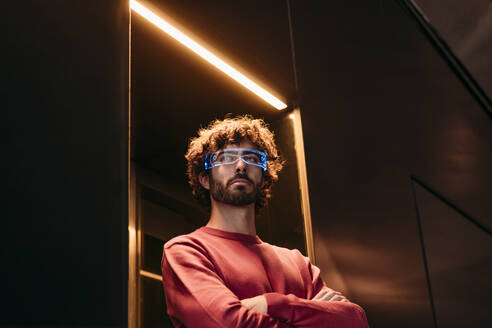 Young man wearing smart eyeglasses standing in elevator - EBBF07852