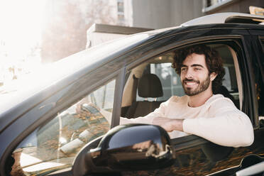 Happy young man driving car on sunny day - EBBF07890