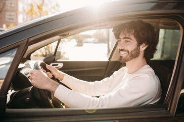 Happy man driving car on sunny day - EBBF07893