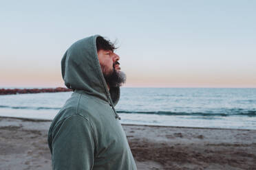 Mann mit Kapuze am Strand stehend - SIPF02887