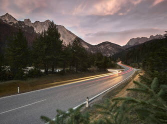Österreich, Fahrzeuglichtspuren entlang der Landstraße in der Abenddämmerung - CVF02292