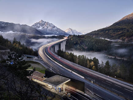 Österreich, Tirol, Fahrzeug-Lichtspuren entlang der Europabrücke in der Abenddämmerung - CVF02293