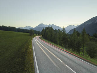 Österreich, Fahrzeuglichtspuren entlang der Landstraße in der Abenddämmerung - CVF02295